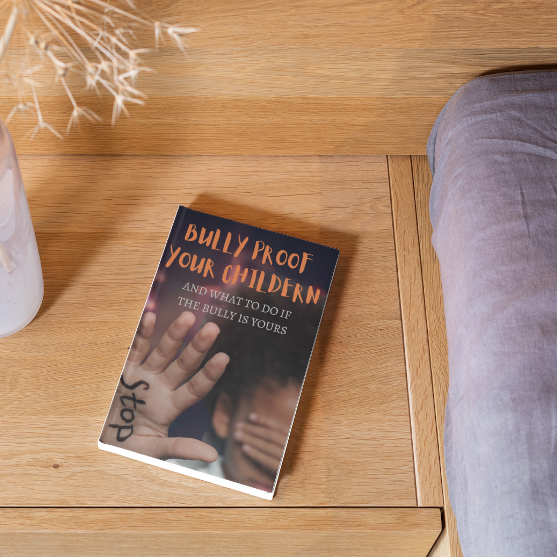 Ebook "Bully Proof Your Children and What to do if the Bully is Yours" on a wooden table by a bed.